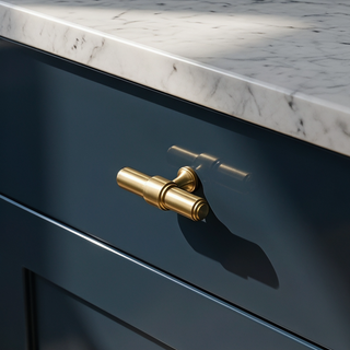 Satin Brass Kensington T-bar knob installed on a dark navy cabinet drawer below marble